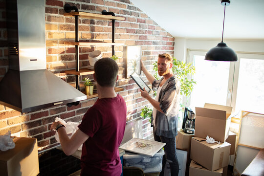 Two men hanging artwork in new kitchen