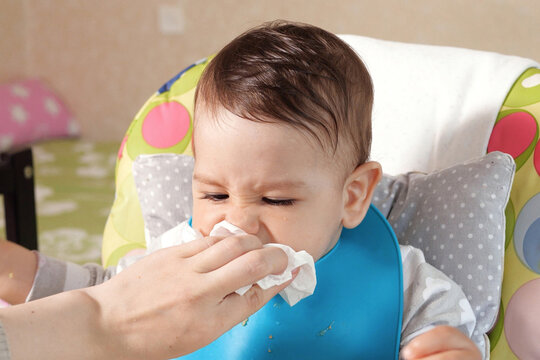 Mom wipes the son drool with a napkin. Baby care, Mother Wipes Baby Mouth With Napkin After Feeding