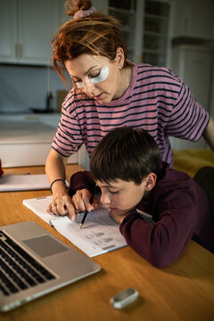 Mother helping son with homework at kitchen table