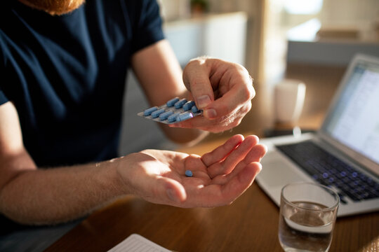Man taking blue pill at home office