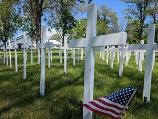 Fototapeta premium White crosses set up in a park to honor fallen American veterans for Memorial Day in a rural Midwestern city. 