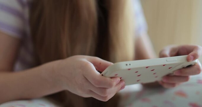 The kid is playing virtual games or watching cartoons on her smartphone. The problem of addiction to gadgets.