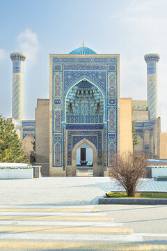 Gur Emir mausoleum facade with turquoise dome and minarets in Samarkand, Uzbekistan. Ornate tilework and grand iwan portal under a clear daytime sky, ideal for travel and heritage publications.