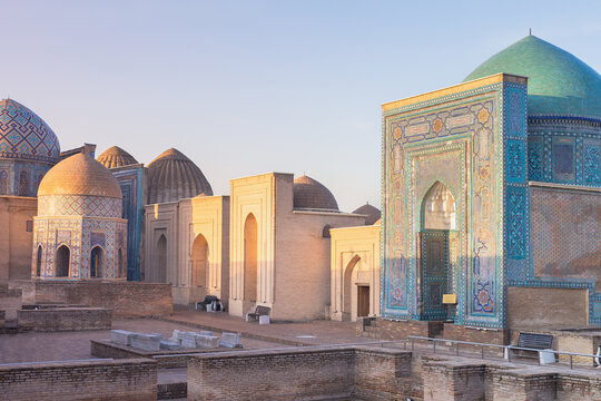 Shah-i-Zinda necropolis mausoleums in Samarkand bathed in warm golden hour light. Ornate tilework facades and turquoise domes define this iconic Uzbekistan landmark, ideal for travel and heritage.