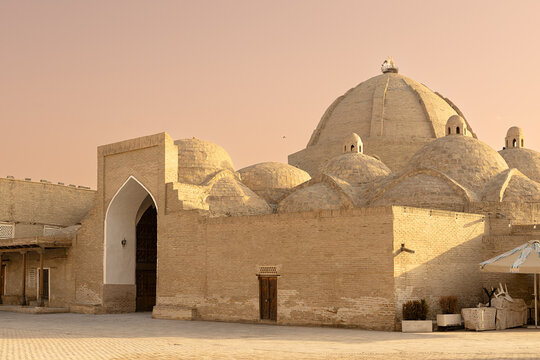 Toqi Zargaron trading dome in Bukhara with multiple brick domes and pointed arch entrance at golden hour. Historic Uzbek architecture ideal for travel publications and cultural heritage projects.