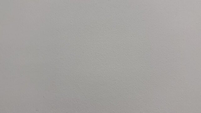 Tilting the camera upwards shows the surface of a cream-colored painted plaster wall.