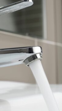 Hand close up water from faucet in sink, faucet,man stop wasting water, flood, running water for washing in hotel bathroom