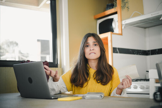 Young Hispanic woman feeling frustrated and stressed about not being able to pay household debts. Financial problems and economic stress concept.