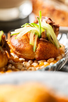 A close-up shot of an authentic Mexican panucho filled with pulled meat and garnished with julienned cucumber, served on a bed of corn kernels.
