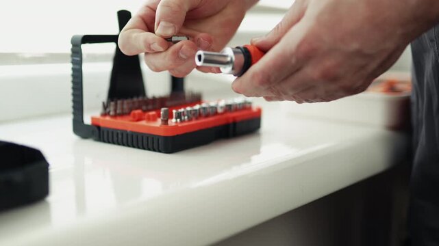 Close-up of a handyman in a jumpsuit assembling a multi-bit screwdriver, professional DIY project, 4K footage