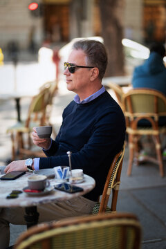 Stylish mature man enjoying coffee at a sidewalk cafe