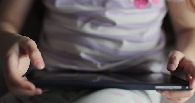 Girl browsing digital tablet computer. Close-up finger scrolling social media. The problem of addiction to gadgets.