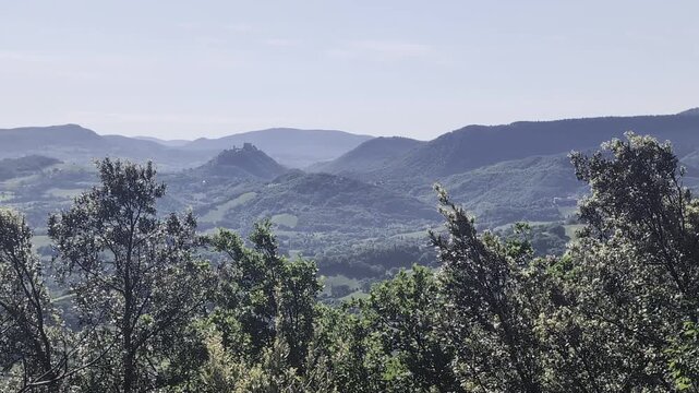 Paesaggio naturale con colline e montagne verdi, alberi in primo piano e cielo limpido, ideale per progetti dedicati alla natura, turismo, escursionismo e ambienti rilassanti