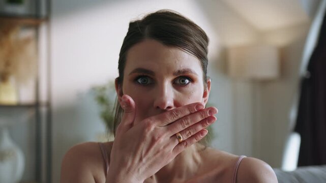 Woman s face with hand covering mouth, expressing shock or disbelief in a home environment. The vivid scene conveys astonishment, emotion and the intensity of unexpected realization