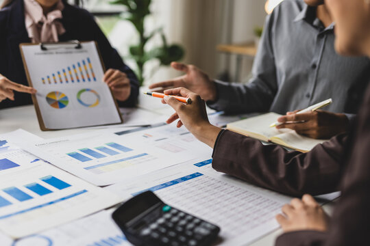 Business professionals discussing financial reports and charts during an office meeting, analyzing data for planning and strategy.