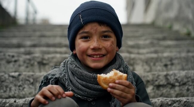 Dirty young boy sits on concrete stairs holding bread, representing poverty, hunger, hardship, resilience, innocence, childhood, struggle, survival, and social inequality