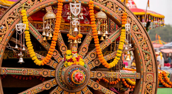 Ornate wooden chariot wheel decorated with marigold garlands and bells