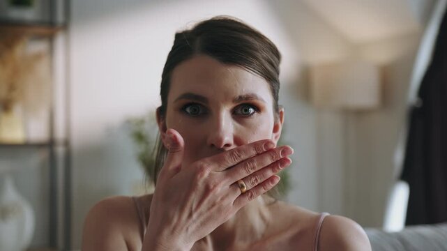 Close-up of a woman's face as she covers her mouth with her hand, showing surprise or disbelief. The vivid detail conveys astonishment, emotion and the intensity of unexpected realization