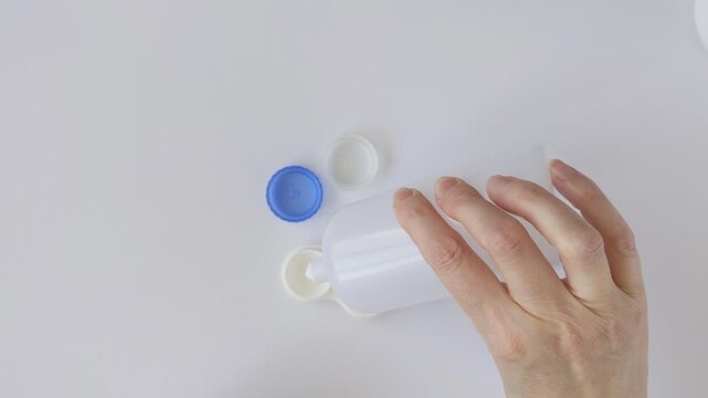 Woman's hands pour contact lens solution into a white plastic container. Concepts of health, ophthalmology, and self-care, for eye care and hygienic lens storage