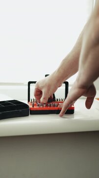 Close-up of a handyman in a jumpsuit assembling a multi-bit screwdriver, professional DIY project, 4K footage