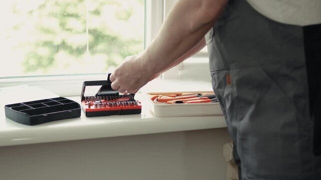 Close-up of a handyman in a jumpsuit assembling a multi-bit screwdriver, professional DIY project, 4K footage