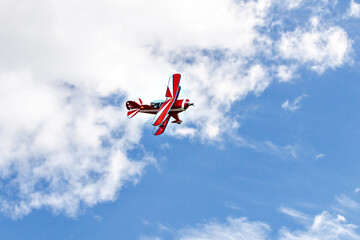 A red aerobatic biplane performing air shows in a blue sky with white clouds. Classic airplanes  © Toni