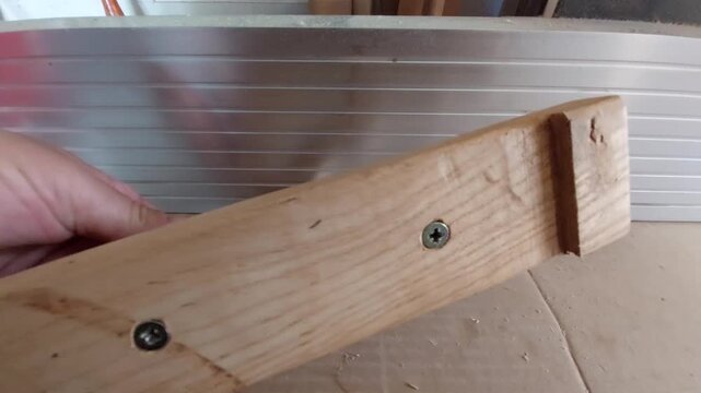 Carpenter showing a handmade wooden push block safety tool for a jointer planed machine