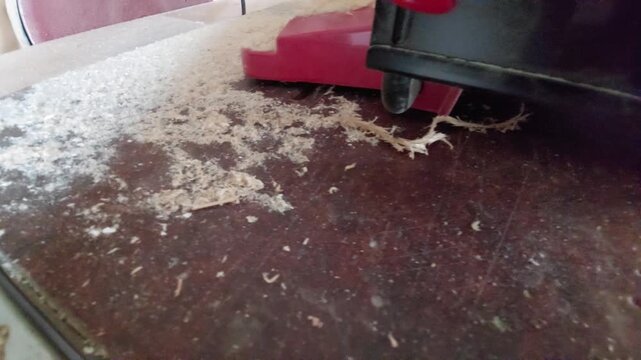 Wood dust and shavings blowing from a working machine onto a workbench