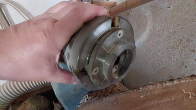 Woodturner checking a metal scroll chuck on a wood lathe next to a raw log