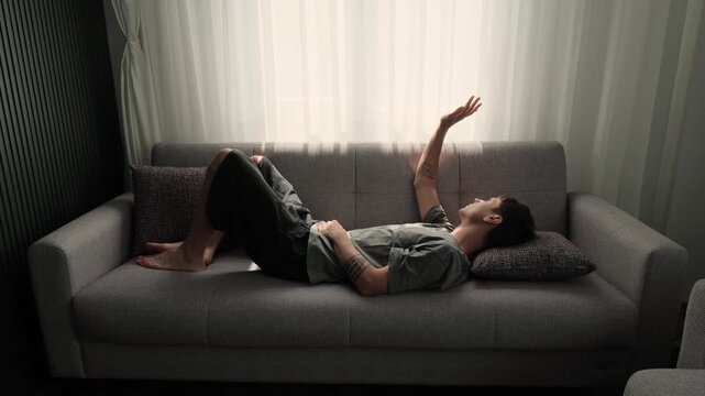 Doing nothing and enjoying peaceful moment at home, young man relaxing on sofa in sunlight, anti productivity lifestyle, slow living and mental reset concept