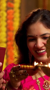 Husband Filming Samai Lighting During Diwali, Indian Married Couple in Saree and Kurta Celebrate Festival by Lighting Traditional Brass Lamp at Night While Smiling and Capturing Moment on Smartphone