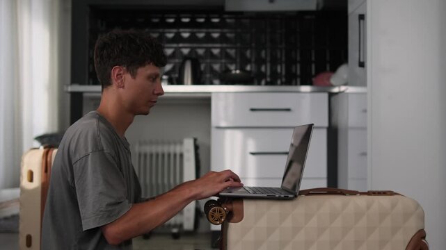 Remote worker using temporary workspace with laptop on suitcases in improvised office, flexible mobile work lifestyle in small apartment