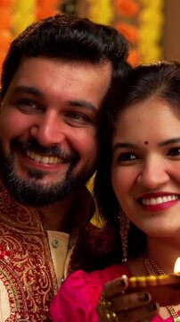 Taking Selfie Lighting Diwali Samai, Indian Married Couple in Saree and Kurta Celebrates Festival Night by Lighting Traditional Brass Oil Lamp as Husband Clicks Selfie on Smartphone with Smiles