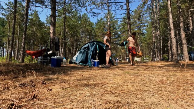 Couple packing camping gear at a forest campsite, time-lapse
