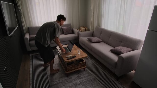 Remote worker changing positions around apartment while working on laptop, authentic freelance routine and modern digital lifestyle in small living space