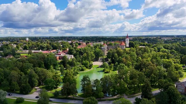 Aerial drone view of Cesis town and its medieval castle ruins, Latvia. Scenic urban park with pond and church on a sunny summer day