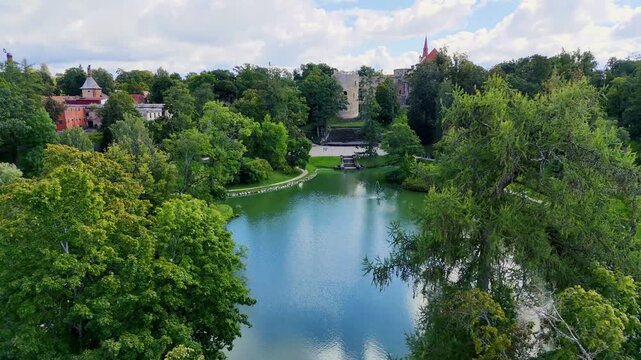 Aerial drone view of Cesis town and its medieval castle ruins, Latvia. Scenic urban park with pond and church on a sunny summer day