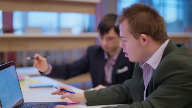 Business colleagues collaborate efficiently on a shared project in a modern office. Individuals with Down syndrome contribute to teamwork, celebrating a high-five for their successful progress.