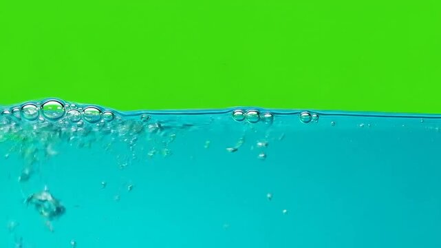 A clear blue liquid surface with rising bubbles against a green background