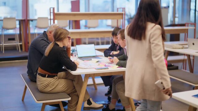 Group of colleagues engages in a dynamic discussion during a collaborative meeting in a modern office space. Businesspeople work together, exchanging ideas and planning future projects around a table.