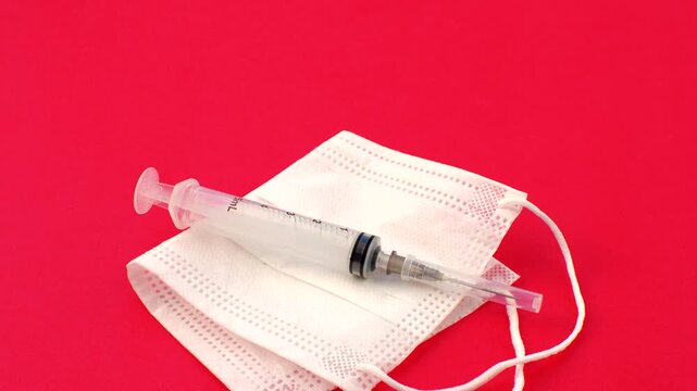 Syringe and white mask, symbols of care and prevention in a clean and impactful composition. Close-up of a syringe and white mask, essential elements in the fight against diseases