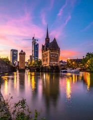 Obraz premium Historic tower and modern buildings at sunset reflect in water