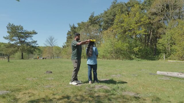 Young man placing a flower crown on a woman's head in a sunny green park