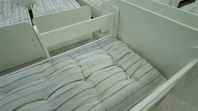 Minimalist wooden bed frame supports comfortable white mattress. Simple functional design fits perfectly into modern bedroom interior