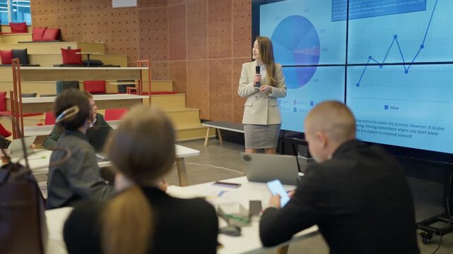 A young businesswoman delivers a presentation on data analytics to her colleagues. Employees actively participate in a corporate seminar featuring market insights.