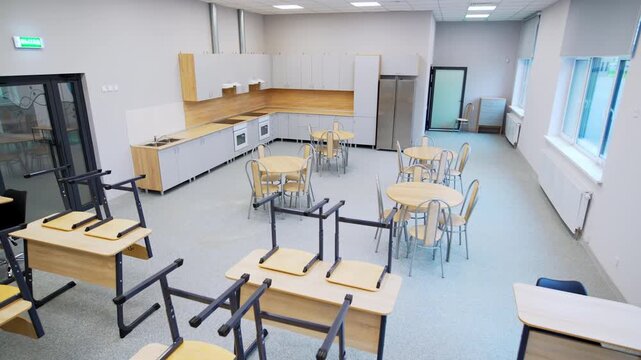 Spacious educational room includes white walls and minimalist ceiling lamps. Organized furniture define contemporary professional facility