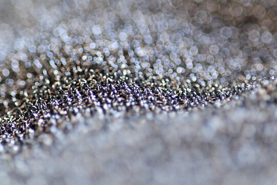 Macro shot of shiny polyester fabric texture with sparkling glitter threads and beautiful festive bokeh.