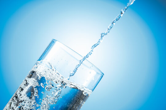 Clear drinking carbonated water pouring into a tall glass.