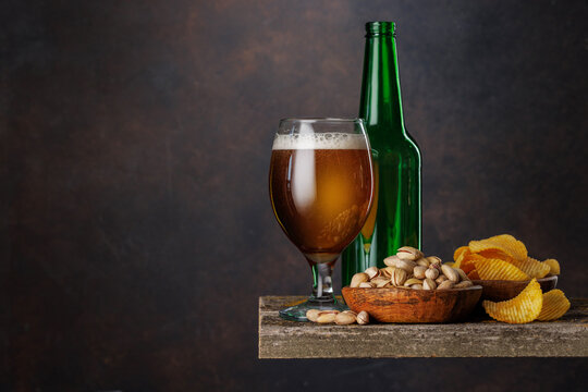 Beer glass with foam and bottle with pistachios