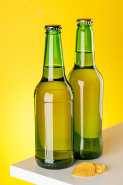 Green glass beer bottles on yellow background minimal studio composition
